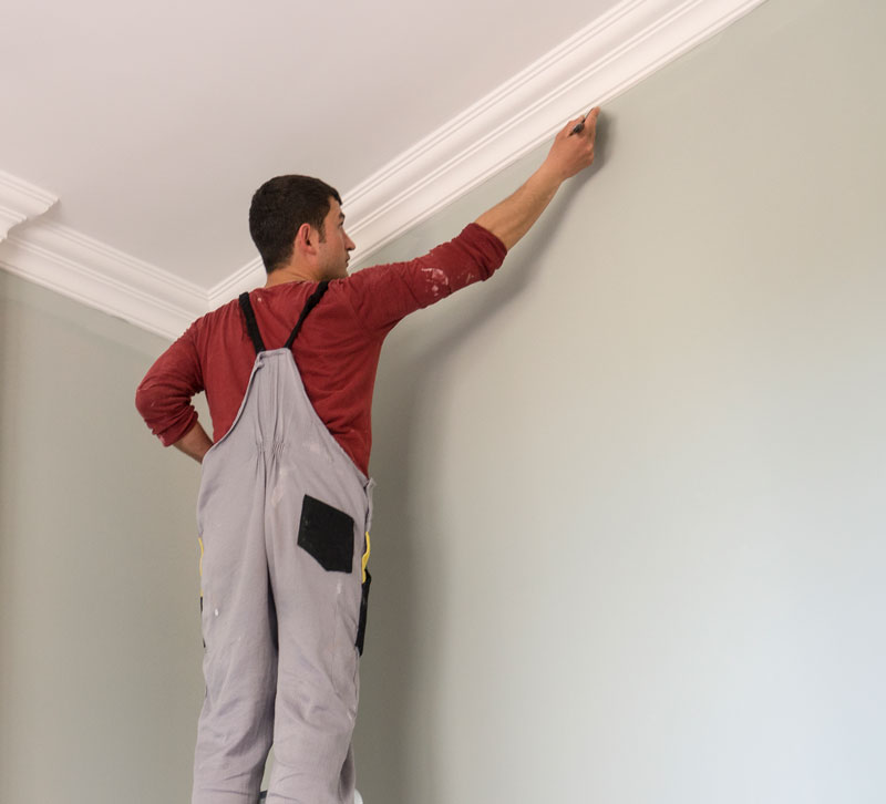 Interior-Painting Man painting a wall up by the crown molding