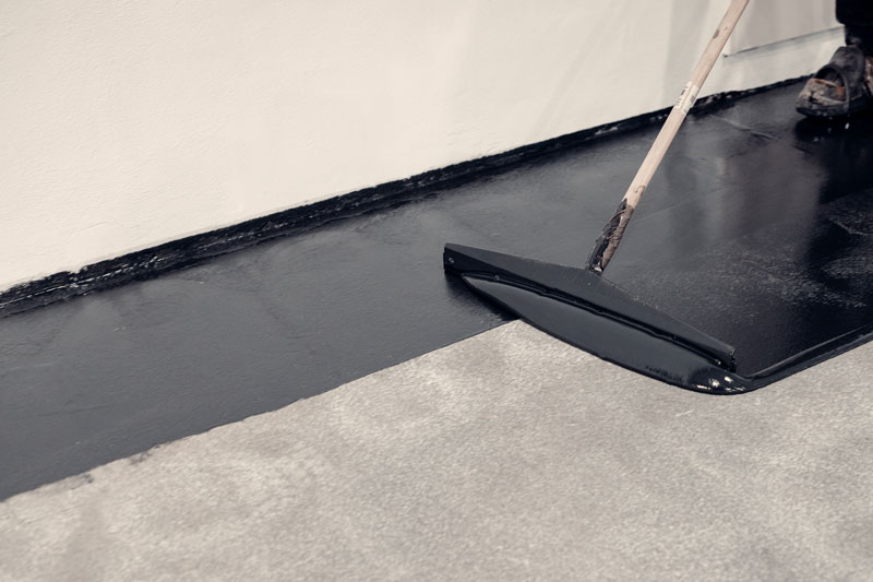 epoxy-flooring someone applying epoxy coating to a cement floor.